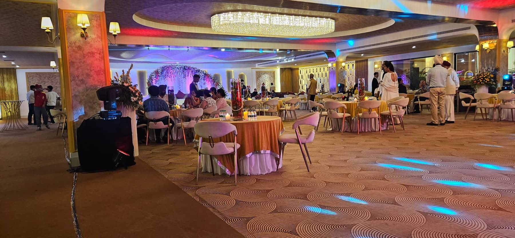 A banqueting room during service, with guests at round tables and a buffet line on the left