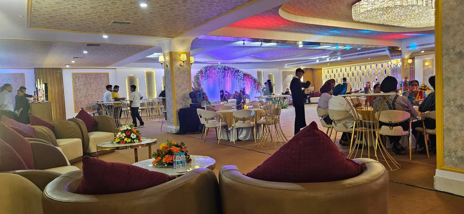 A lounge area within the banqueting floor with sofas, poseur tables and a floral arch behind the seating