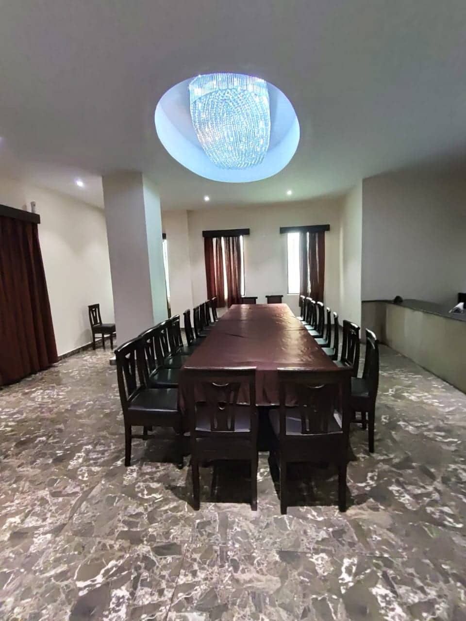 A boardroom-style meeting room with a dark wood table, leather chairs and a decorative ceiling medallion