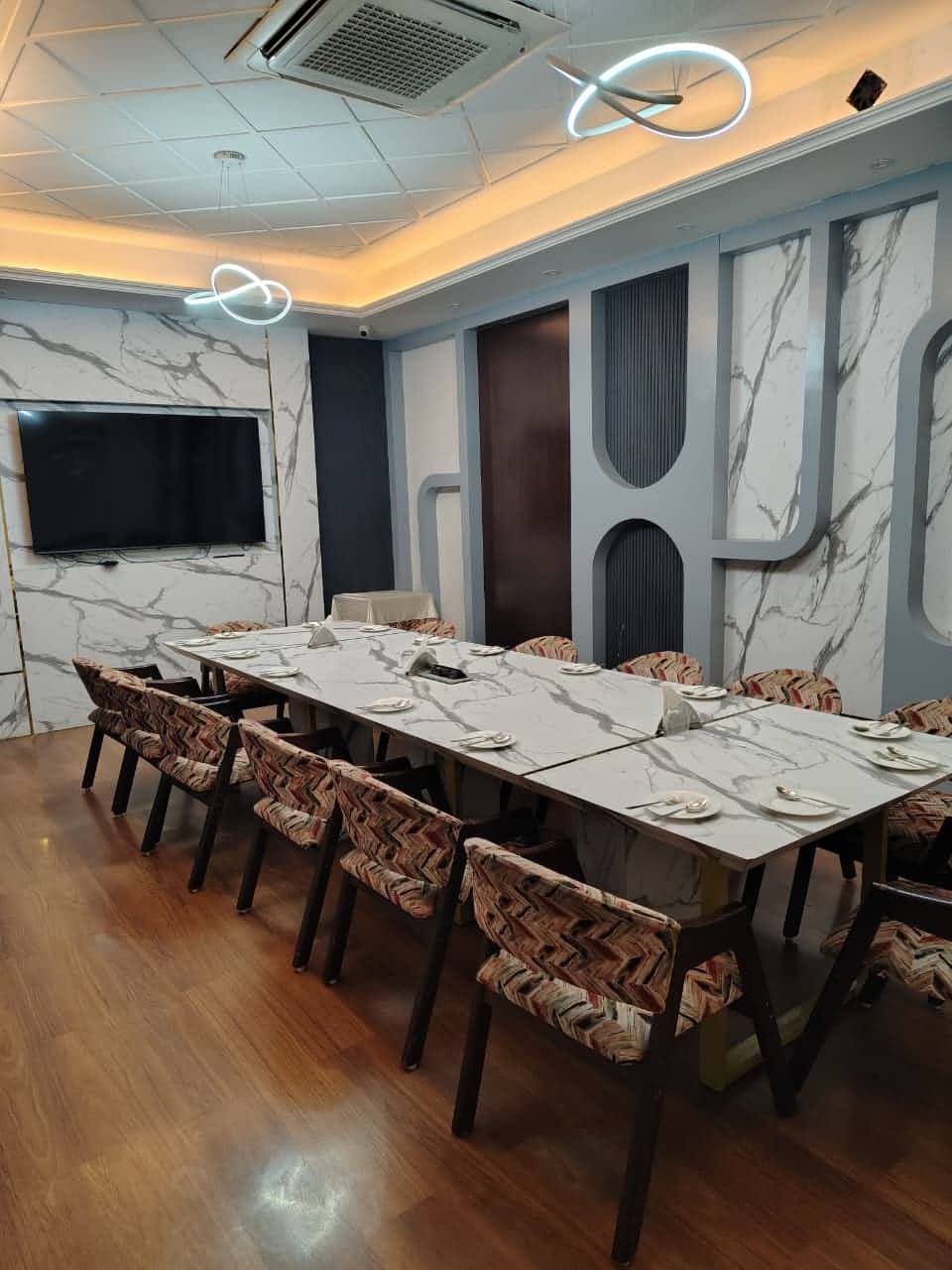 A meeting room configured in a U-shape with padded chairs and a wall-mounted screen