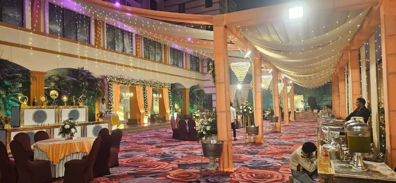 A large covered outdoor venue with draped fabric between pillars, festoon lighting and buffet counters along the side