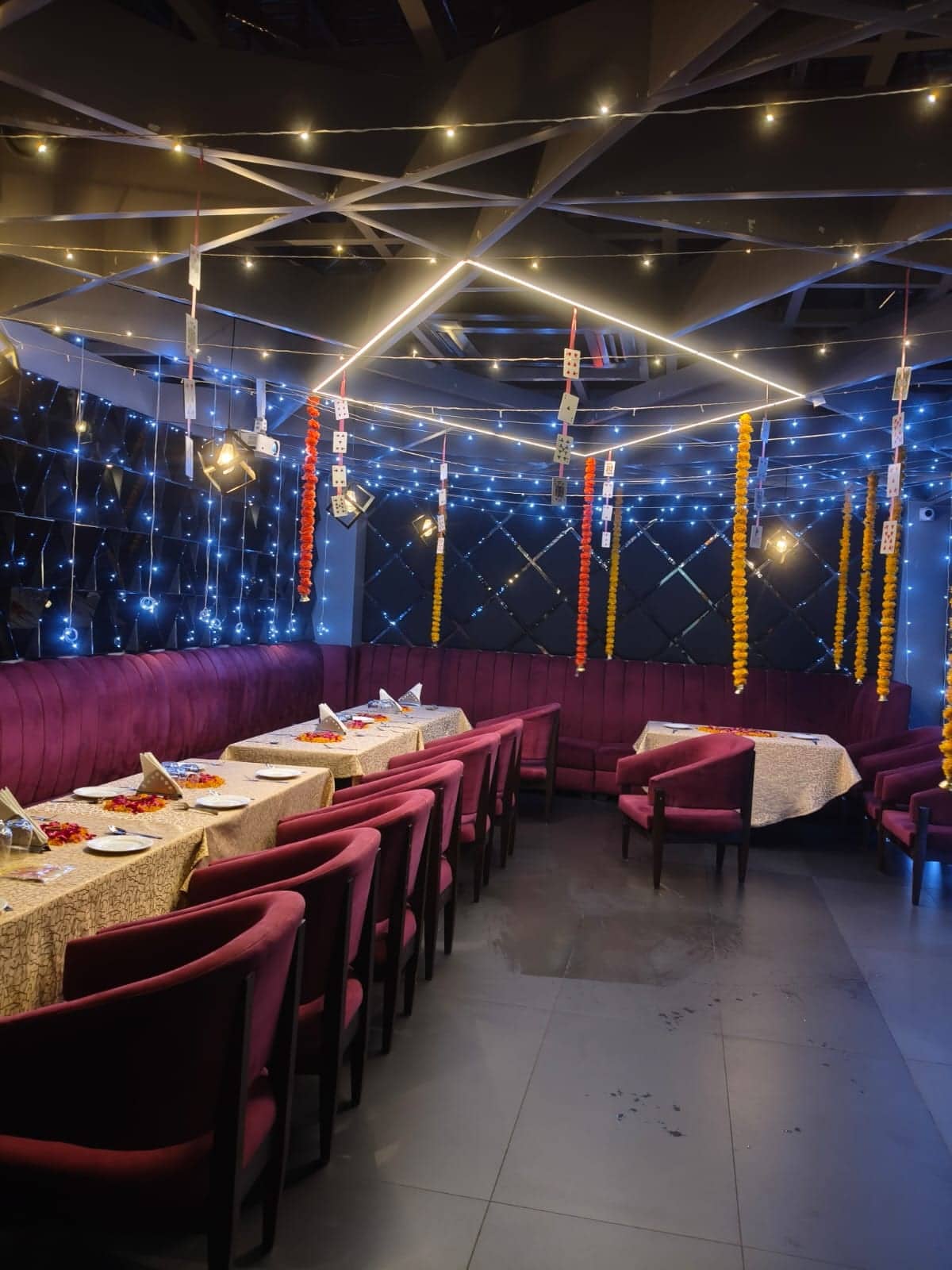 An enclosed private hall with a draped ceiling, blue accent lighting and velvet-seated dining tables